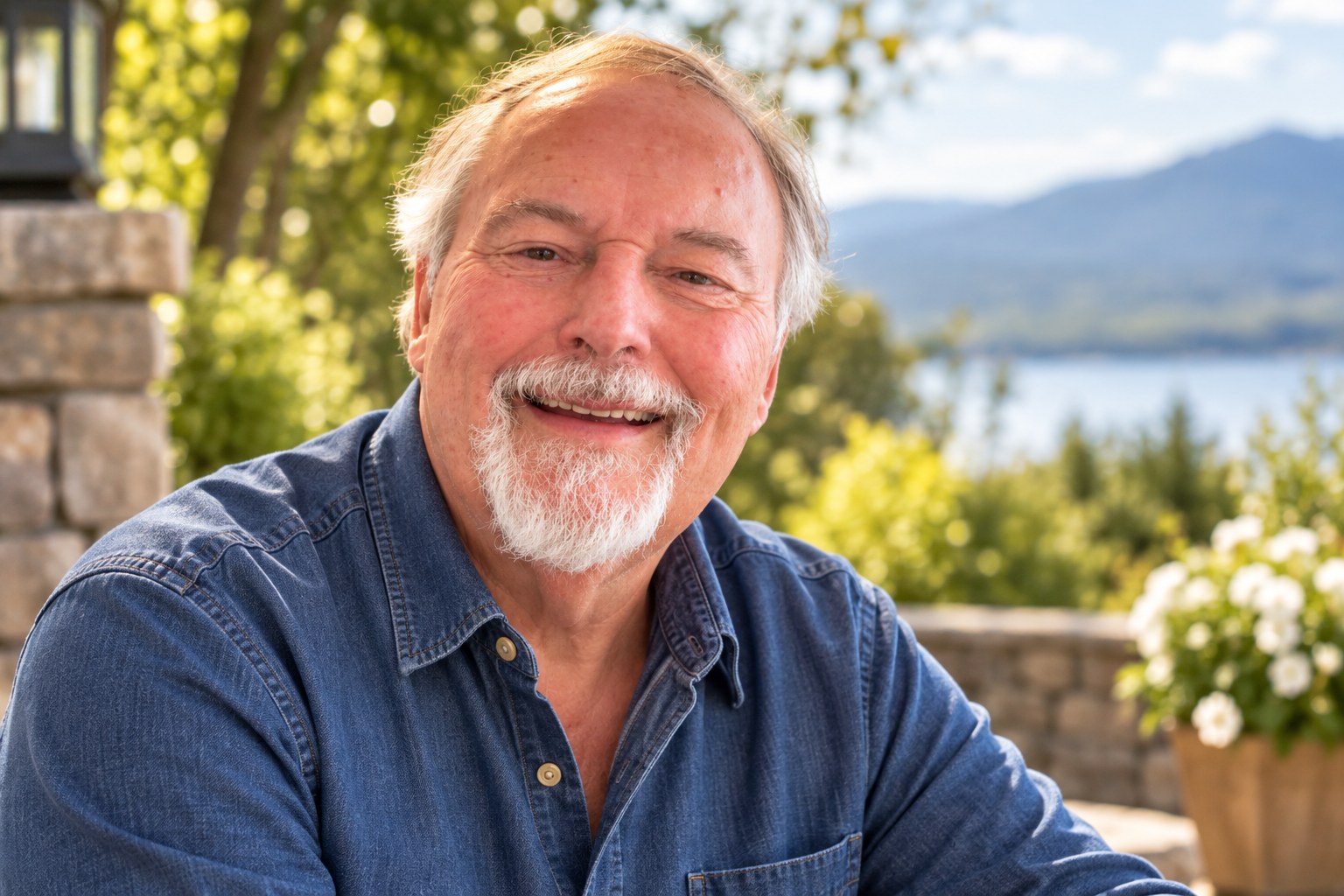 Dr. Jorge Parrott smiling outdoors in a denim shirt with a lake and mountains behind him